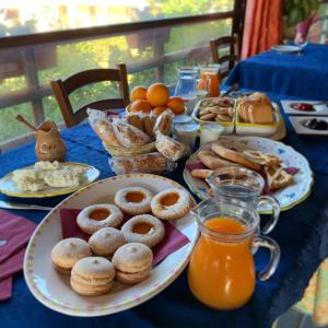 una mesa con platos de donas y zumo de naranja en Agriturismo Muru Idda en Budoni