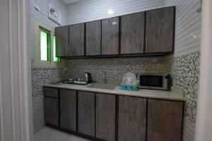 een keuken met houten kasten, een wastafel en een magnetron bij Jasmine Beach Hotel Suites in Yanbu