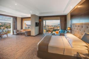 ein Hotelzimmer mit einem großen Bett und einem Wohnzimmer in der Unterkunft The Biltmore Tbilisi Hotel in Tbilisi City