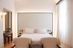 een slaapkamer met een groot wit bed en 2 stoelen bij S Paul City Hotel in Limassol