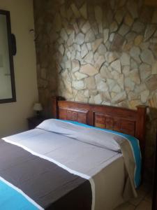 a bed in a room with a stone wall at Elorina Sicily Home in Siracusa