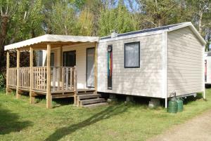 a tiny house with a porch and a gazebo at Camping de Kergo in Ploemel
