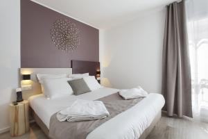 a bedroom with a white bedspread and white pillows at L'alcôve Hôtel in Nice