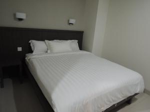 1 cama con sábanas blancas y almohadas en una habitación en Harlys Residence, en Yakarta