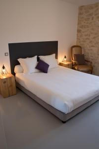 um quarto com uma cama grande e uma cadeira em Hôtel Le 23 em Sauternes