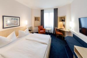 a hotel room with a bed and a desk and a television at IntercityHotel Magdeburg in Magdeburg