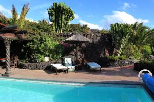 una piscina con patio y sombrilla en Casa Feliz, en Tías