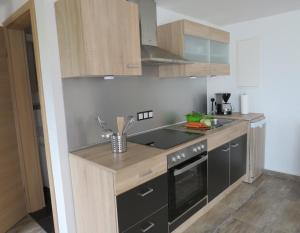 a kitchen with black appliances and wooden cabinets at Ferienwohnung Saarwiesen in Merzig