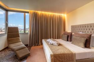 a bedroom with a bed and a chair and windows at NEYA Lisboa Hotel in Lisbon