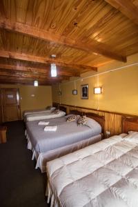 a row of beds in a room with wooden ceilings at Hostal Alcázar in Puerto Natales