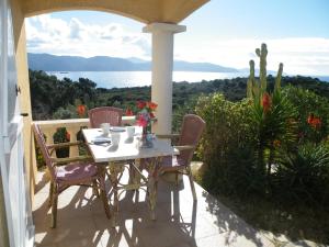 a table and chairs on a porch with a view of the ocean at Villa Liamone Studio für 3 Personen , 400 m vom Strand, Pool, Klimaanlage in Sagone