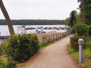 a path next to a lake with boats in the water at Ferienwohnung La Calma, Zeuthen in Zeuthen