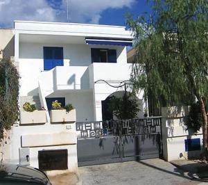 una casa bianca con una recinzione davanti di Appartamento Torre Pali a Torre Pali