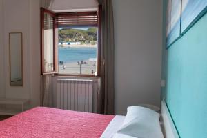 モンデッロにあるMondello Beach - Rooms By The Seaのビーチの景色を望むベッドルーム1室(ベッド1台付)が備わります。