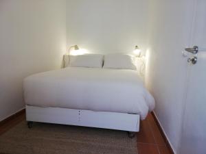 a white bed with two pillows on it in a room at Casa Típica Algarvia in Cabanas de Tavira