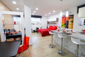 a kitchen and living room with a red bed at Folco Studio Apartment in Piazza Armerina