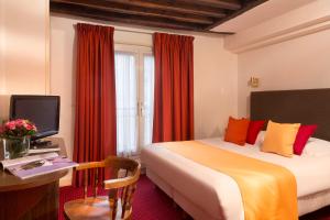 Habitación de hotel con cama, escritorio y TV. en Hôtel Saint Roch, en París