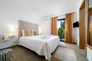 a bedroom with a white bed and a large window at Quinta das Andorinhas in Carvoeiro