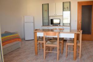 una cucina con tavolo, sedie e frigorifero di Appartamento Idra a Rivabella