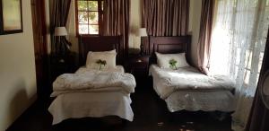 een kamer met twee bedden met bloemen erop bij Forest Creek Lodge & Spa in Badfontein