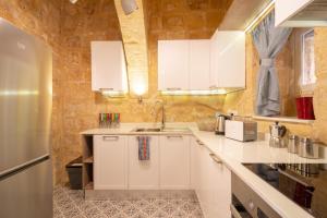 a kitchen with white cabinets and a stone wall at 16 lettings - charming character house in Birgu +70 photos