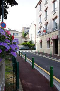 een straat met een hek en bloemen aan de kant van een weg bij Hôtel du Parc in Malakoff