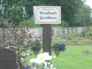 een bord op een paal in een tuin met bloemen bij Woodlands House in Farranfore
