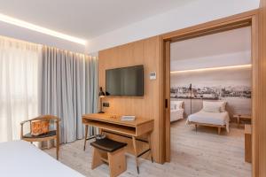 a hotel room with a desk and a bed and a television at Ibis Styles Heraklion Central in Heraklio