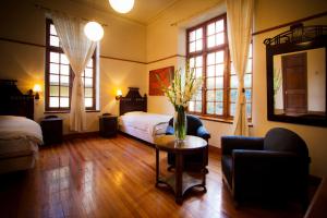 Un dormitorio con una cama y una mesa con un jarrón de flores en Hotel Boutique El Consulado, en La Paz
