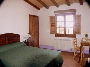 1 dormitorio con cama, escritorio y ventana en Mas del Salin en Cornudella