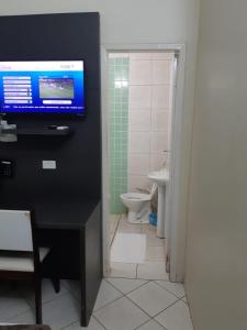 a bathroom with a tv on the wall and a toilet at Hotel Express - Leva e busca no aeroporto grátis 24 horas in Várzea Grande