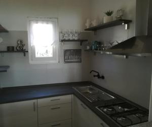 eine Küche mit einem Herd, einem Waschbecken und einem Fenster in der Unterkunft Poseidon Holiday Guesthouse in Žirje