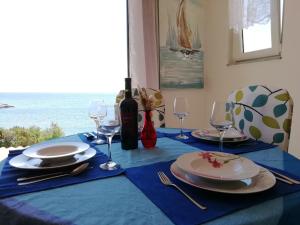 einen Esstisch mit einem blauen Tischtuch und einer Flasche Wein in der Unterkunft Poseidon Holiday Guesthouse in Žirje