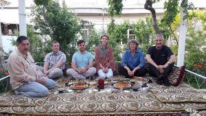 a group of people sitting around a table with food at Nurobod Guesthouse in Bukhara