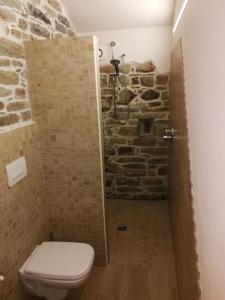 a bathroom with a toilet and a stone shower at MIRUTT by Keyhole Selection in Castelmezzano