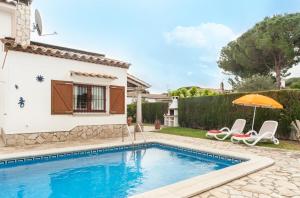 une villa avec une piscine, 2 chaises et un parasol dans l'établissement Villa del sol, à L'Escala