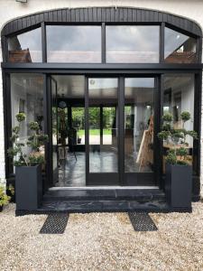 une extension en verre d'une maison avec des plantes en pot dans l'établissement La Ferme de la Place, à Bouvines