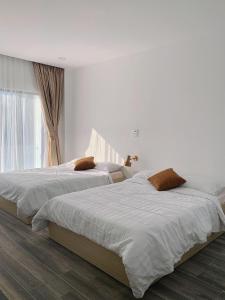 - 2 lits dans une chambre blanche avec fenêtre dans l'établissement Flora Hotel - Phan Rí Cửa, à Ấp Lâm Lộc