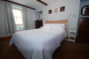 a bedroom with a large white bed and a window at Driftwood Cottage in Banff