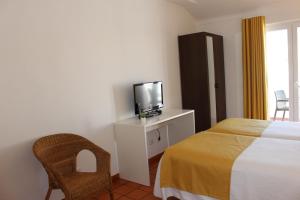 1 dormitorio con 1 cama, TV y silla en Guest House - Duna Parque Group en Vila Nova de Milfontes