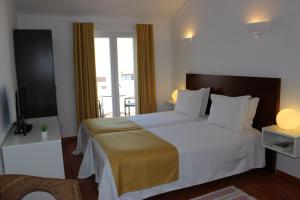 a hotel room with a bed and a balcony at Guest House - Duna Parque Group in Vila Nova de Milfontes