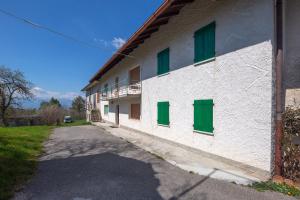 ein weißes Gebäude mit grünen Fenstern und einer Auffahrt in der Unterkunft Casa Fiorellino in Belluno