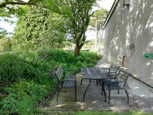 a table and chairs sitting next to a building at Rockville Amlwch LL68 0TE, UK Apartment in Llanfflewyn