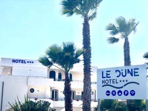 a hotel with palm trees in front of a building at Hotel Le Dune in Sampieri