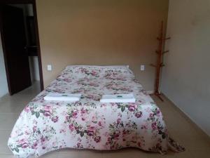 a bedroom with a bed with a pink floral bedspread at Pousada Recanto do Sossego- Serra da Canastra in Vargem Bonita
