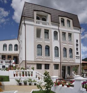 un gran edificio blanco con techo marrón en Pensiunea Eden, en Băile Olăneşti