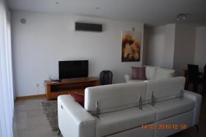 a living room with a white couch and a tv at Quarportugal in São Martinho do Porto