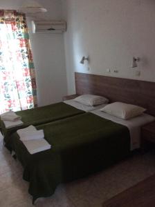 a bedroom with a large green bed with towels on it at Fania Apartments in Kardamaina