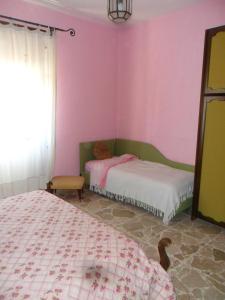 ミラッツォにあるB&B PinkHouseのピンクの壁のベッドルーム1室(ベッド2台付)