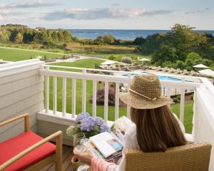 a woman sitting on a balcony looking out at the ocean at Inn By the Sea in Cape Elizabeth